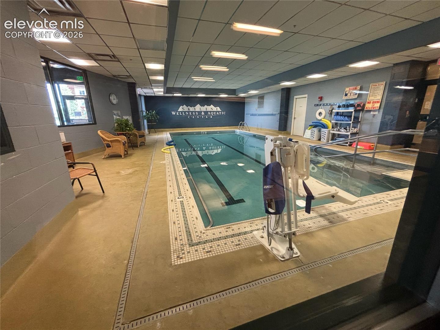Indoor swimming pool featuring an integrated hot tub and perimeter tile detailing