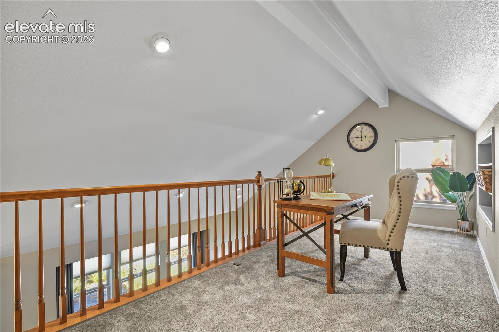 Vaulted ceiling featuring a natural wood-finish railing, recessed lighting, wall-to-wall carpeting, and a built-in recessed wall shelving unit
