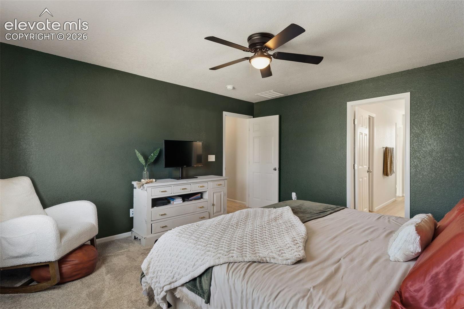 Interior room featuring textured walls, a ceiling fan with light fixture, and light-toned carpeting