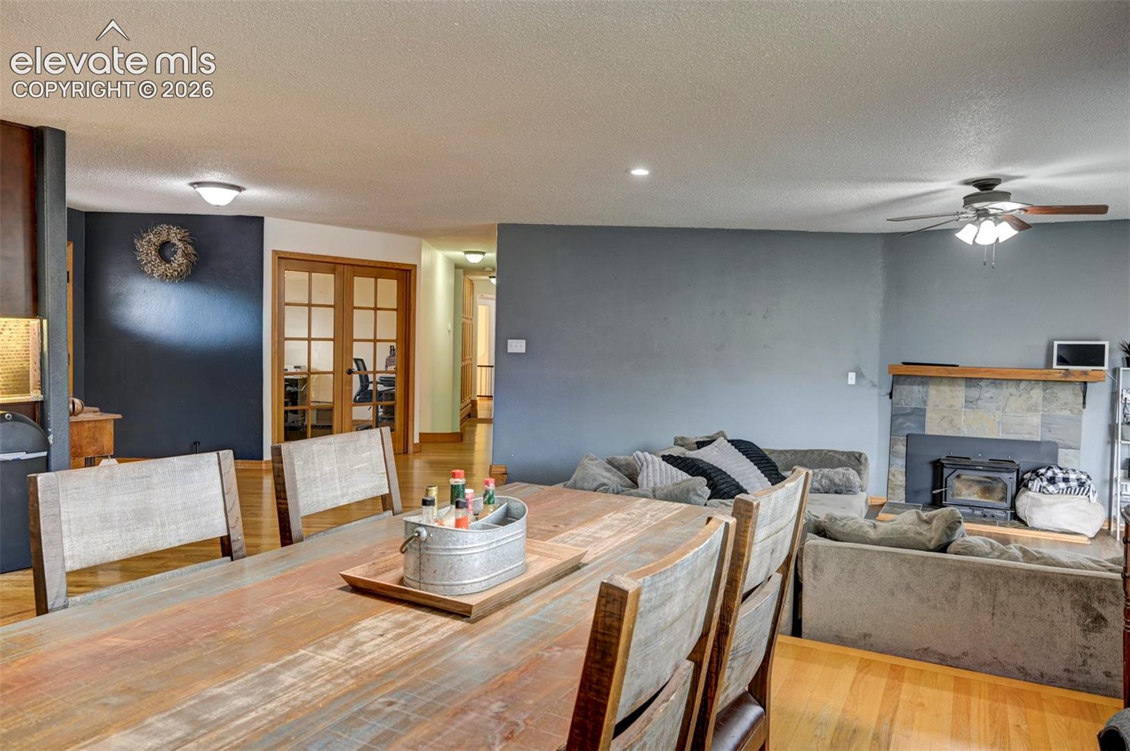 Hardwood flooring throughout, recessed lighting, and a slate-tiled fireplace with a wood-burning insert
