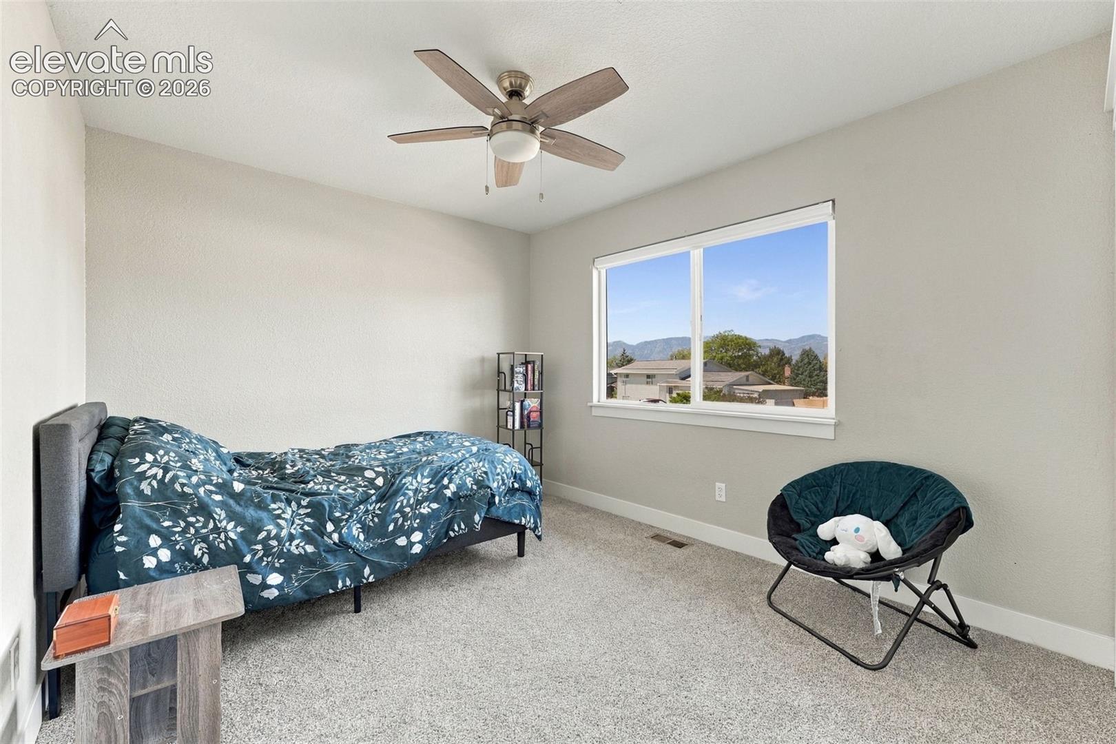 wood-finish ceiling fan, broad window, and light-toned carpeting