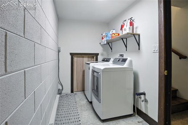 Laundry area featuring separate washer and dryer and concrete block wall