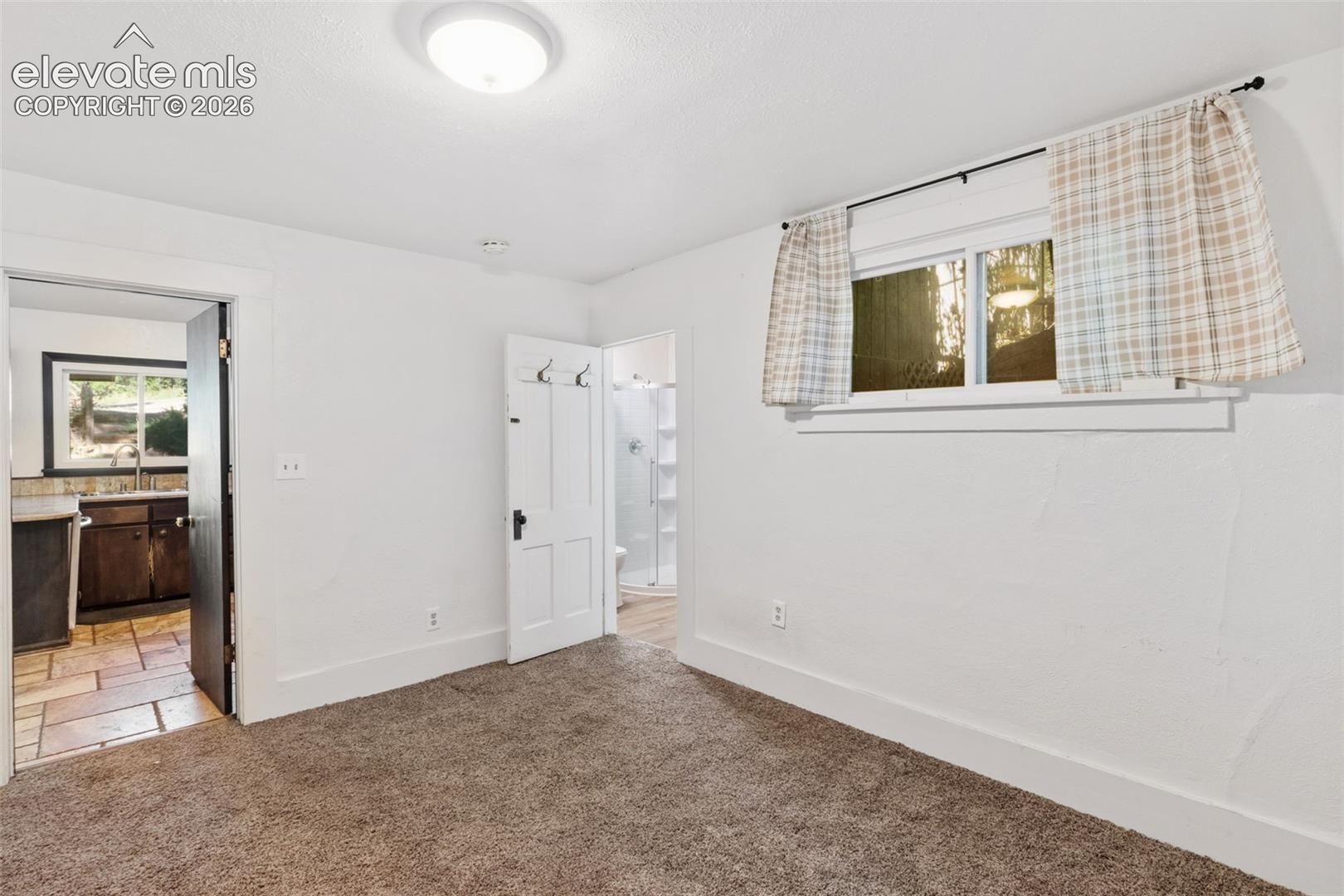 Neutral-toned carpeting, white interior walls, flush-mount ceiling lighting, multi-pane window, and white interior doors