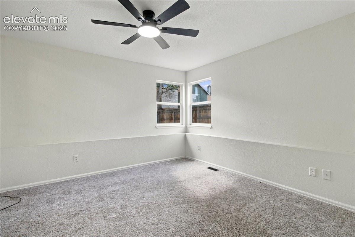 Neutral walls featuring horizontal wainscoting, wall-to-wall carpeting, and a central ceiling fan with integrated lighting