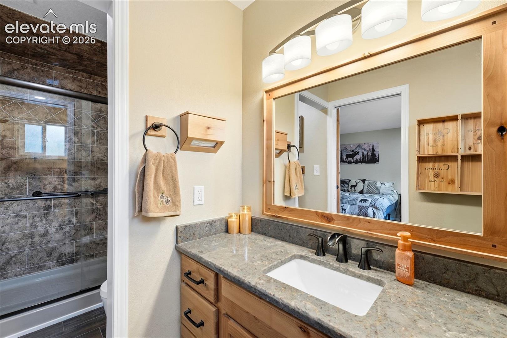 Vanity with a rectangular sink, dark hardware, and a wood-framed mirror