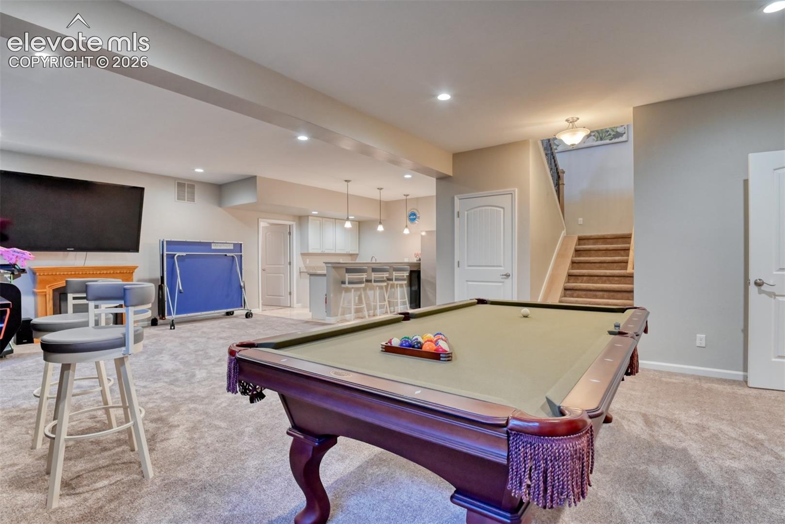 Finished lower level with recessed lighting, integrated wet bar featuring pendant lighting, and carpeted flooring.