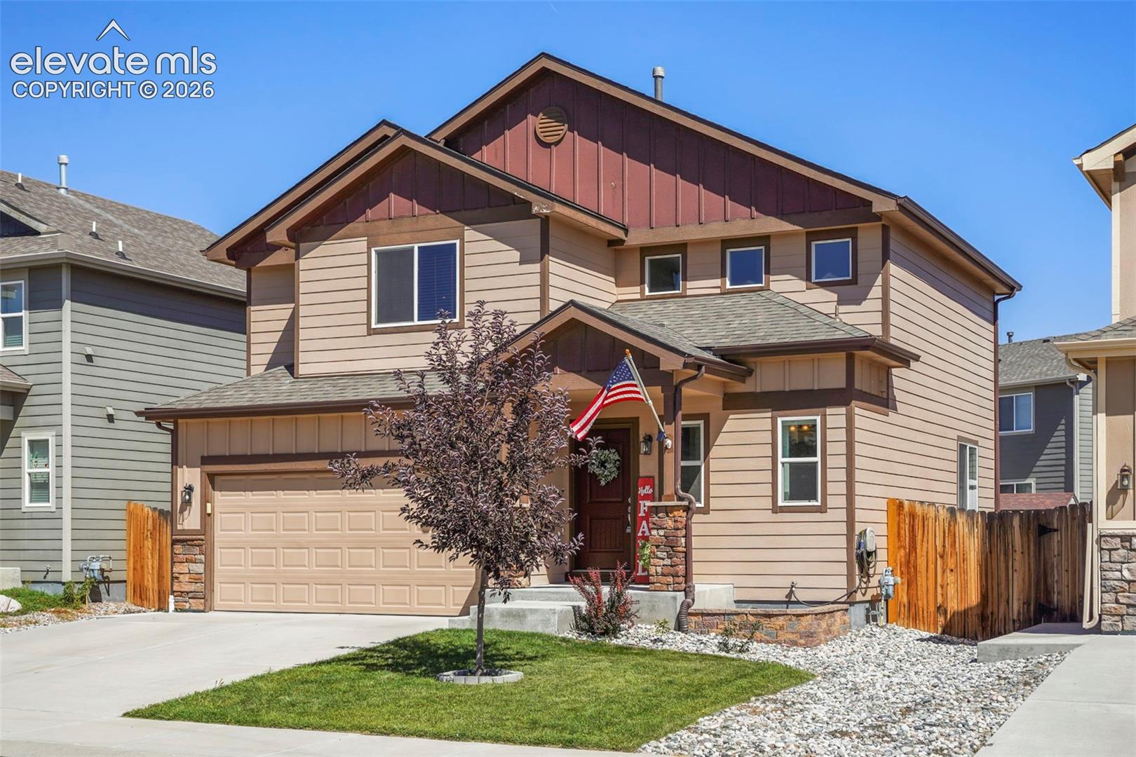 Two-story residence featuring composite siding, an attached two-car garage, a covered entry, and a stone accent facade