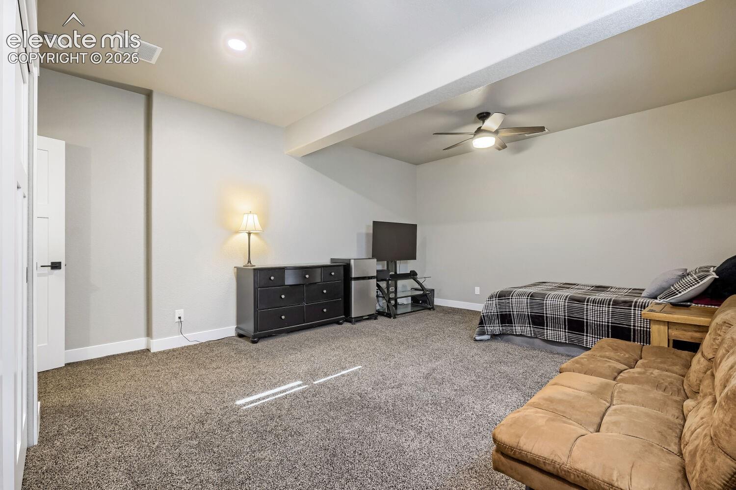 Recessed lighting and a ceiling fan fixture illuminate the carpeted floor