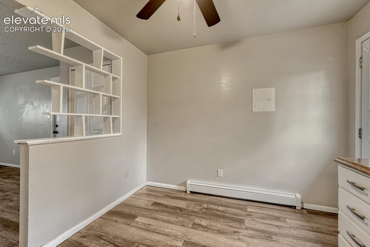 Built-in decorative shelving, wood-finish flooring, ceiling fan, and baseboard heating
