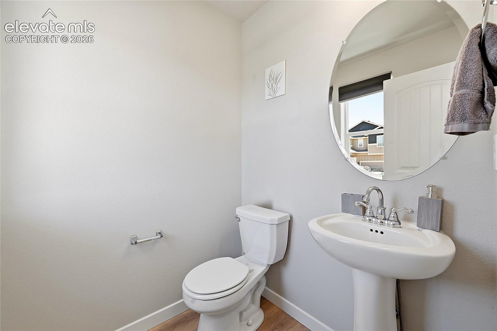 Pedestal sink with chrome fixtures and a circular mirror