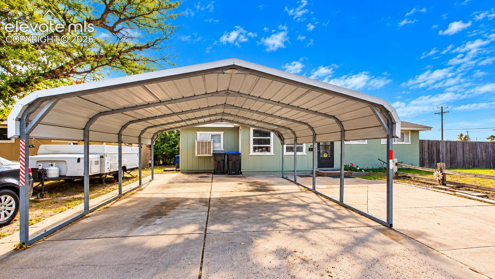 Generously sized metal carport providing covered parking and protection from the elements, complemented by an expansive concrete driveway offering additional parking space.