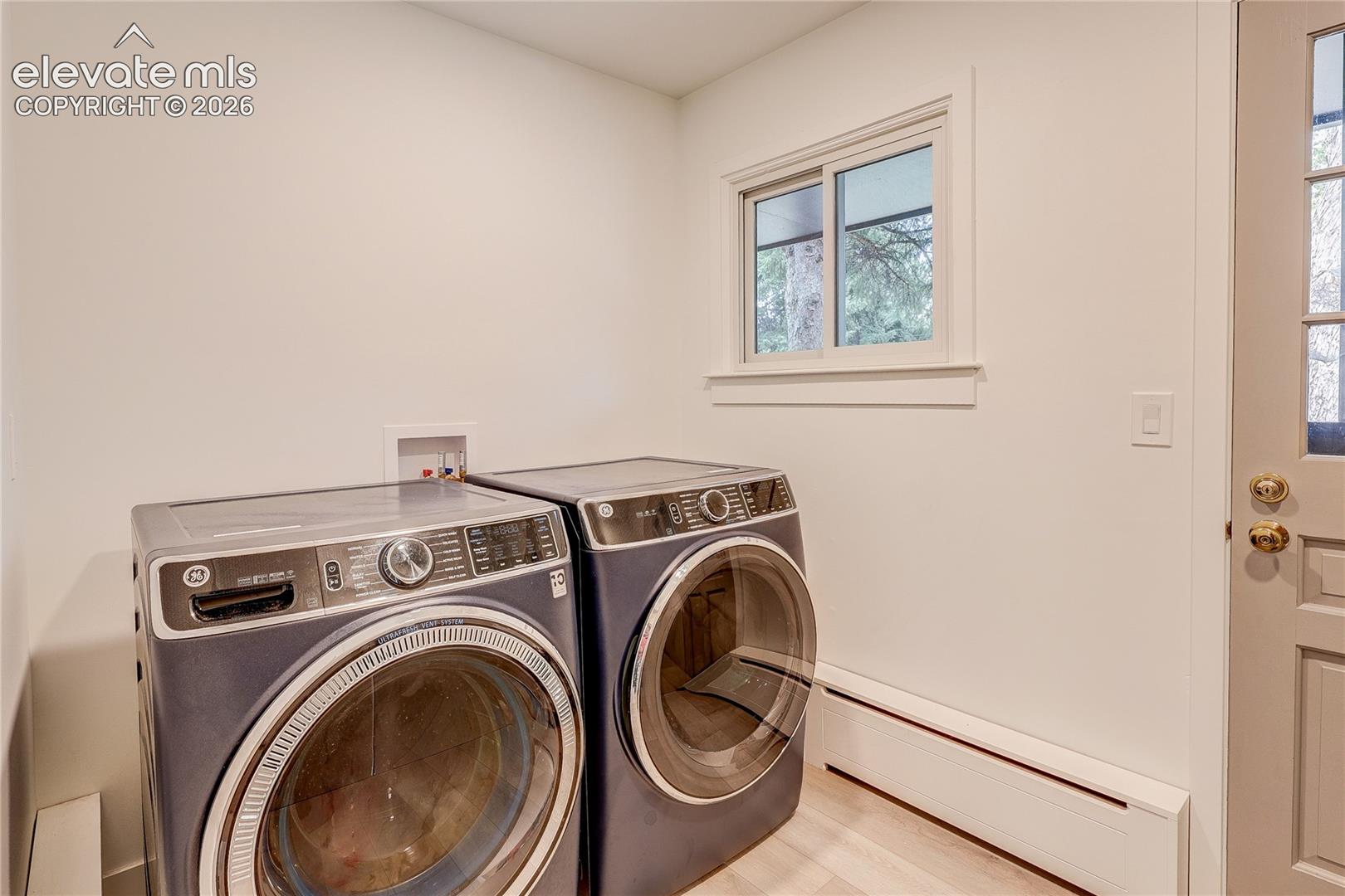 Laundry area with a light wood-finish floor and a white framed window