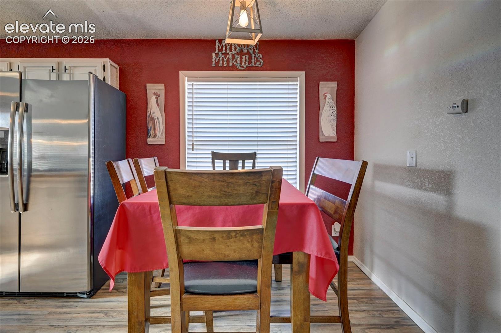 Dining space with light wood-type flooring, a textured wall, and a textured ceiling