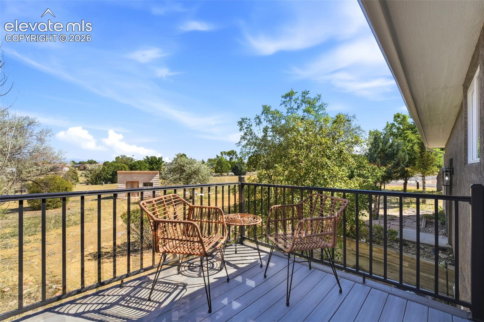 Outdoor balcony featuring composite decking, black metal railing, and an exterior light fixture