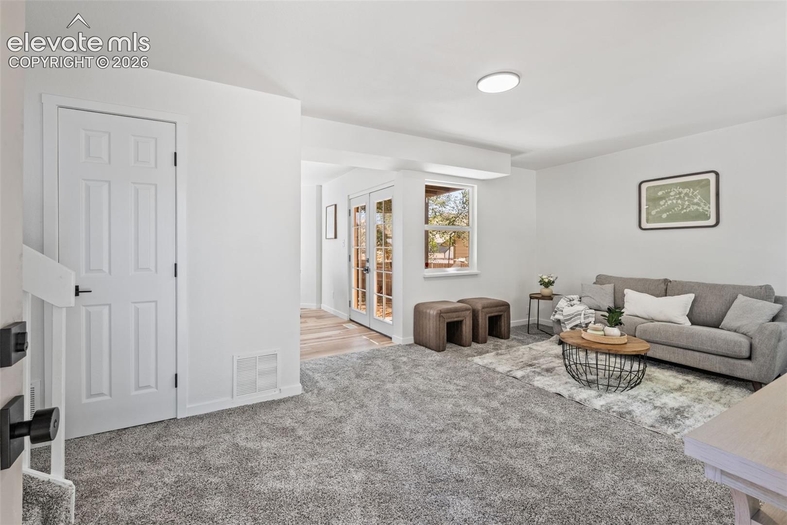 Interior space featuring neutral wall tones, plush wall-to-wall carpeting, recessed ceiling lighting, a six-panel door, and double glass-paned doors with exterior visibility
