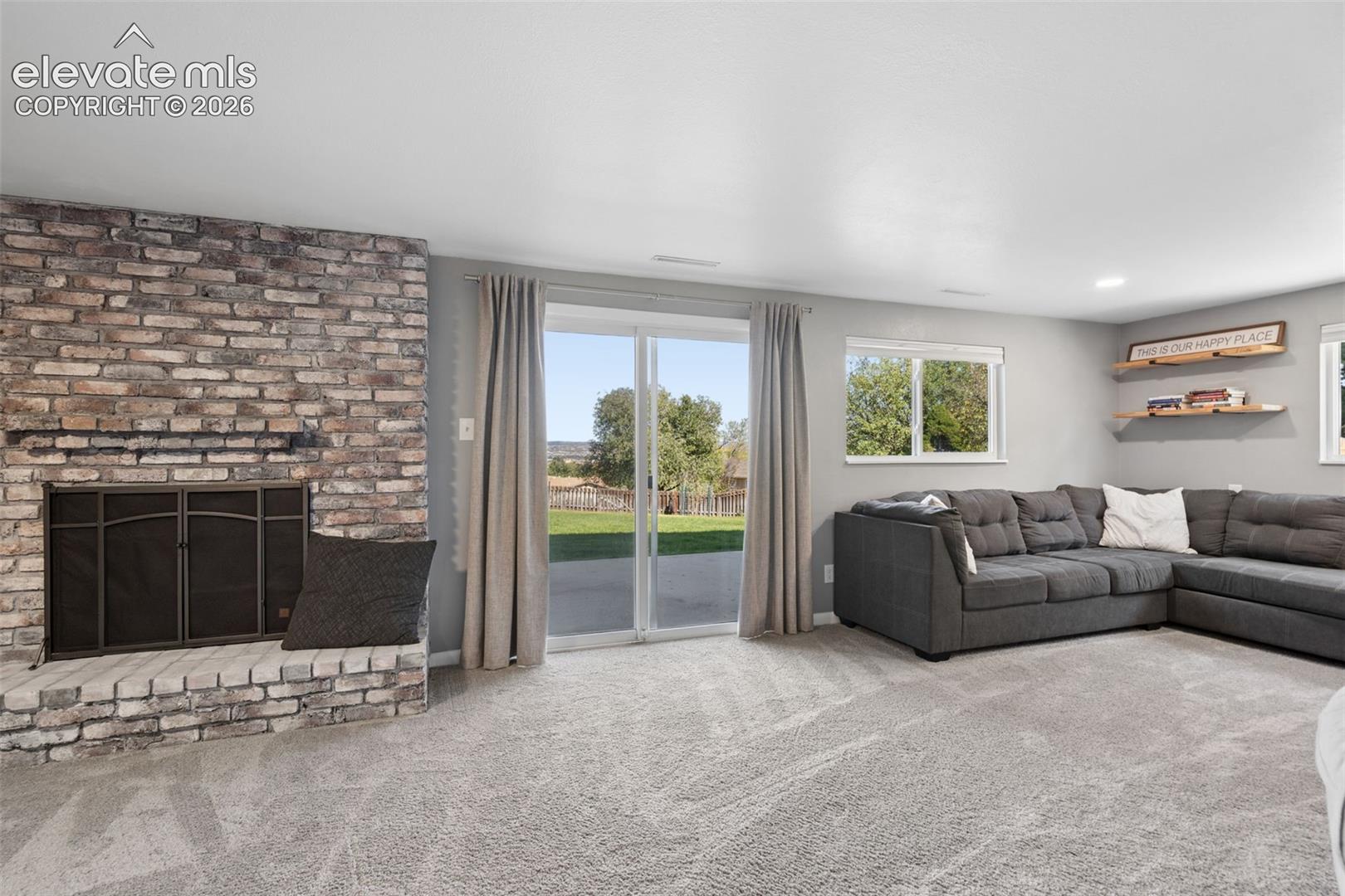 Basement Walk Out Full-height brick masonry fireplace with a raised hearth, glass sliding doors, wall-to-wall carpeting, and recessed shelving