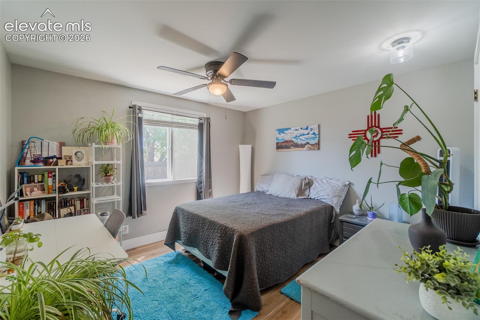 Spacious room featuring wood-finish flooring, a window offering natural light, and a ceiling fan with integrated lighting