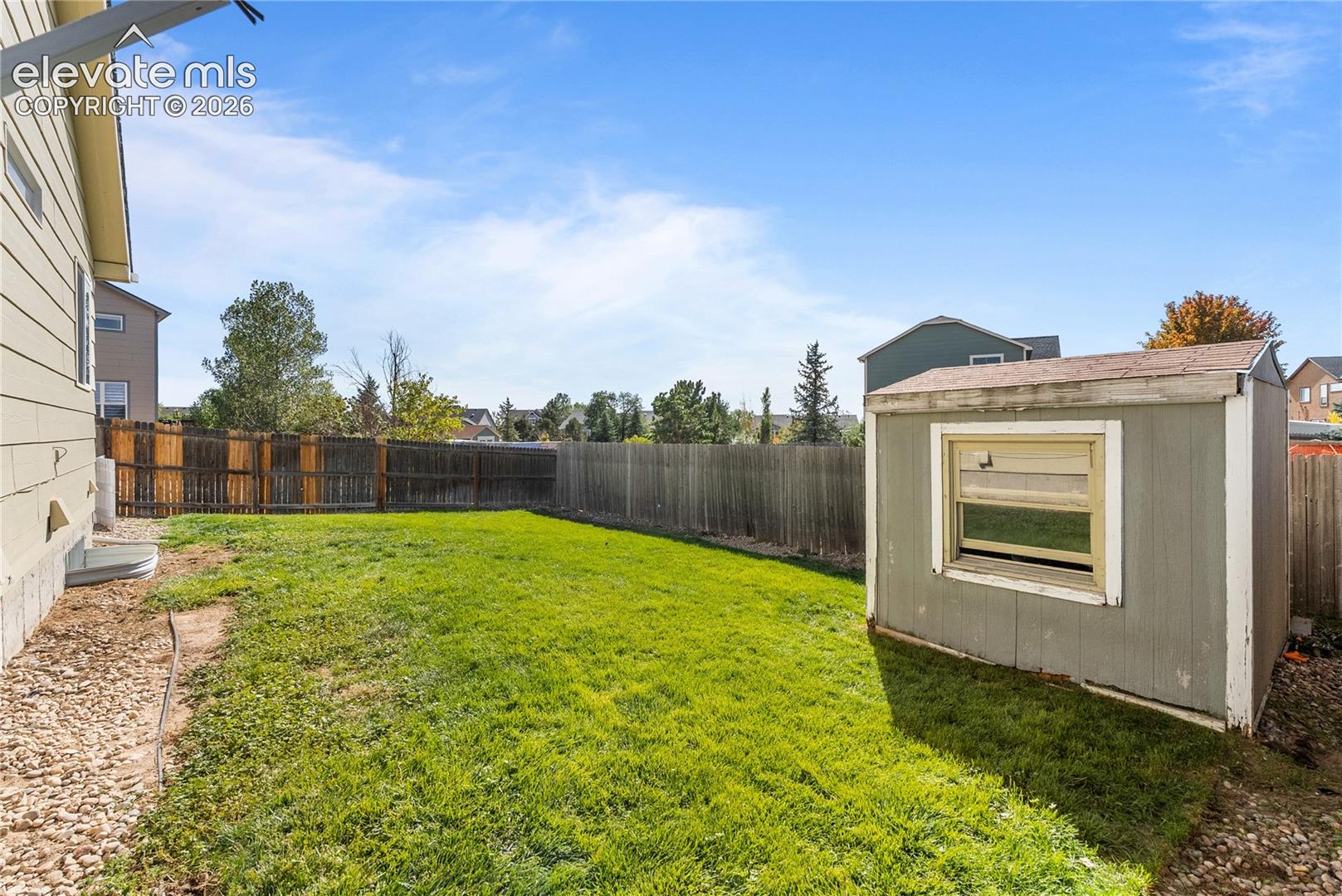 Expansive grassy yard area with a wood-panel fence