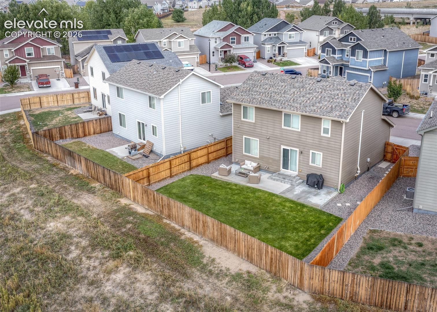Two-story residence featuring composite siding, a concrete rear patio, a fenced yard, and a shingle roof