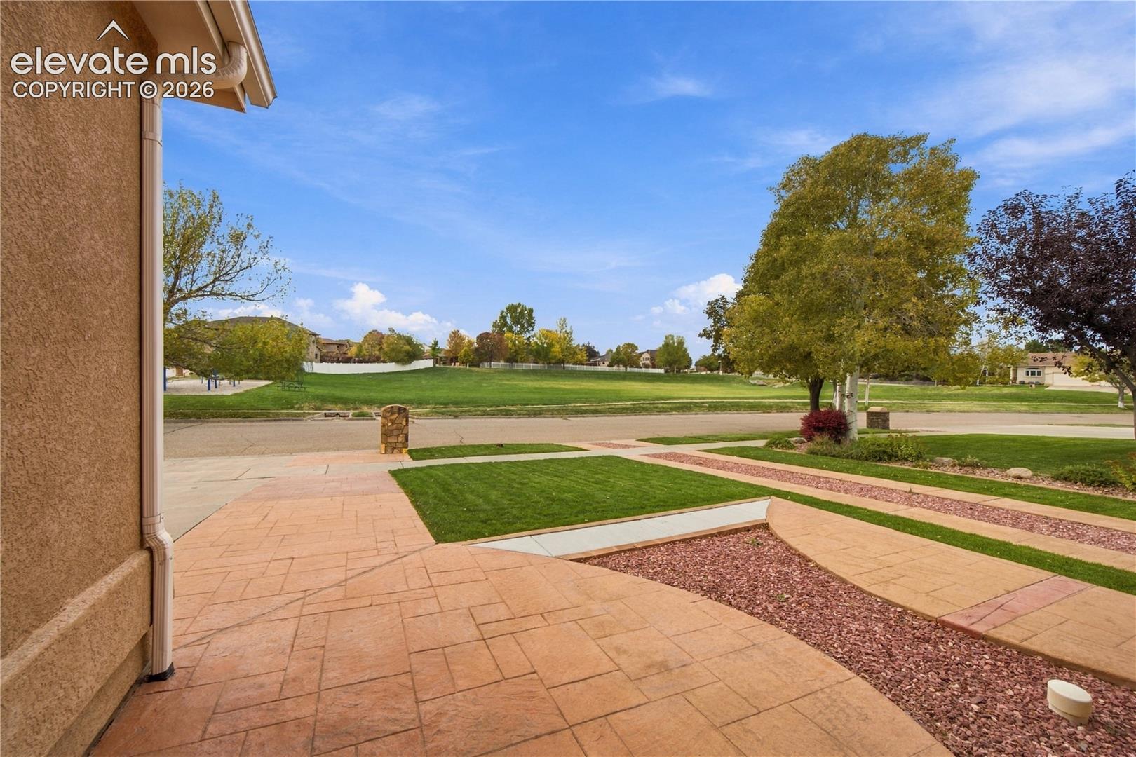Exterior space featuring stamped concrete paving, decorative stone ground cover, and manicured turf