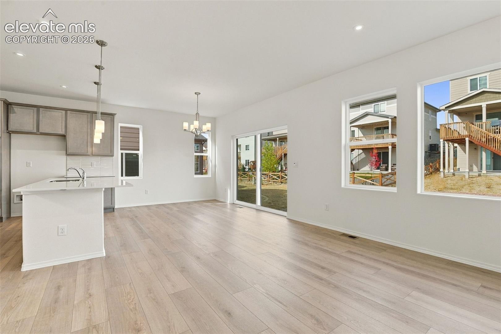 Open-concept kitchen featuring an island with a light-toned countertop, wood-finish flooring, recessed lighting, and glass sliding doors