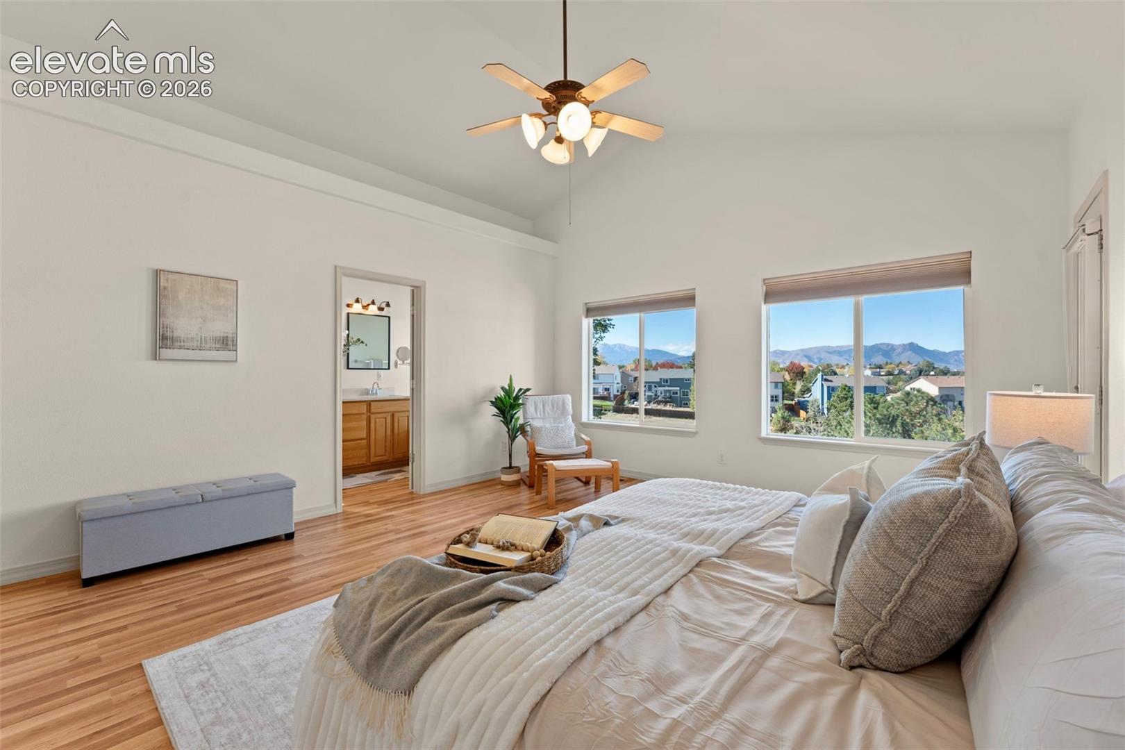 Vaulted ceilings, wood-finish flooring, dual windows, and a ceiling-mounted light fixture with fan