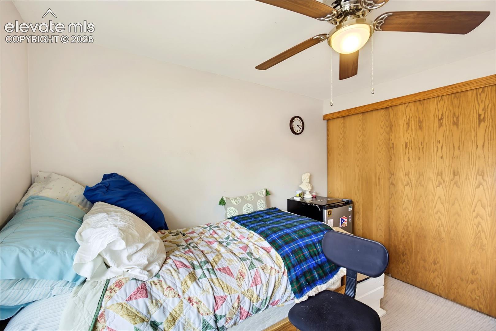Wood-finish sliding closet doors, ceiling fan with integrated lighting, and neutral wall tones