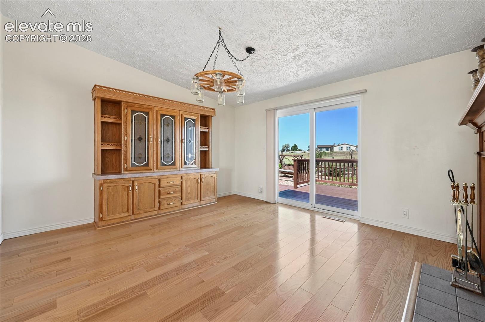 Wood-finish flooring, built-in wooden cabinetry, fireplace with hearth, sliding glass door, and exterior deck