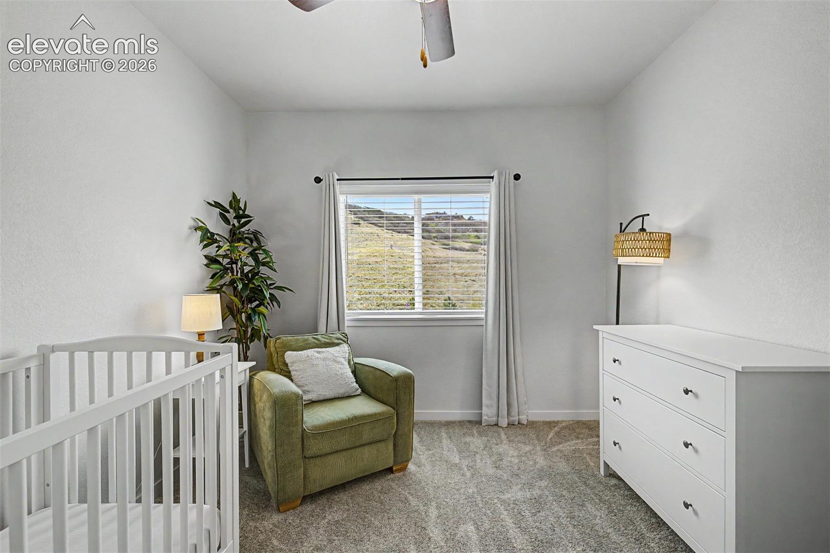Soft and sweet, this bedroom has been lovingly set up as a nursery, with a white crib, plush reading chair, and a window that frames a peaceful hillside view — the perfect quiet corner for a little one's earliest dreams.