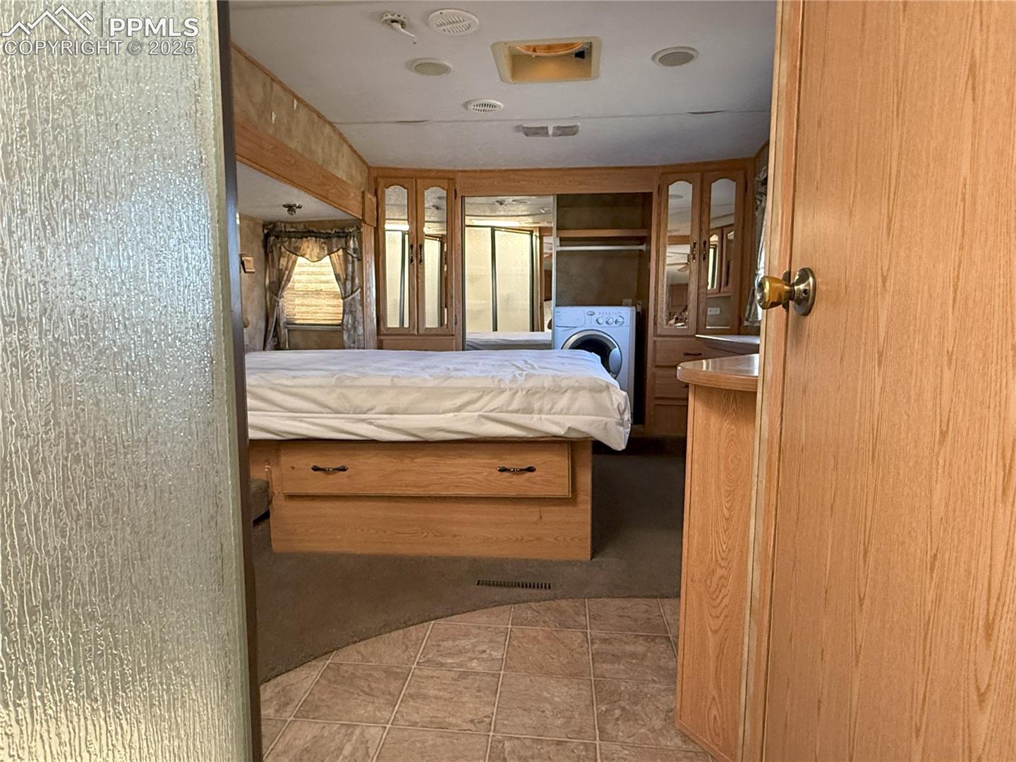 Bedroom featuring washer / dryer, ensuite bathroom, and light tile patterned floors