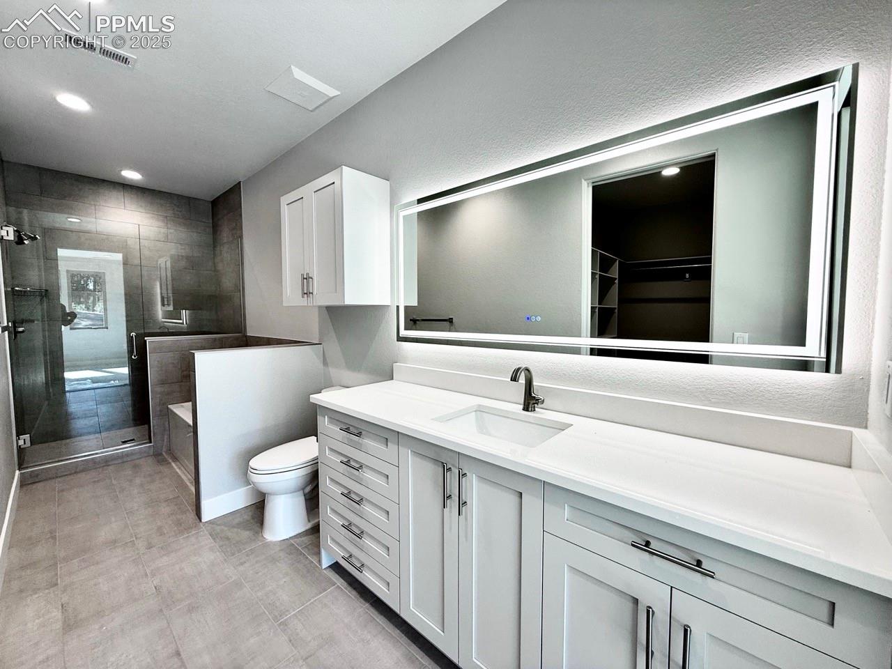 Luxurious Primary Bathroom with Quartz Countertop, Deep Soaking Tub, Tiled Shower with Bench and Glass Door, and a Heated Mirror to avoid Fogging.