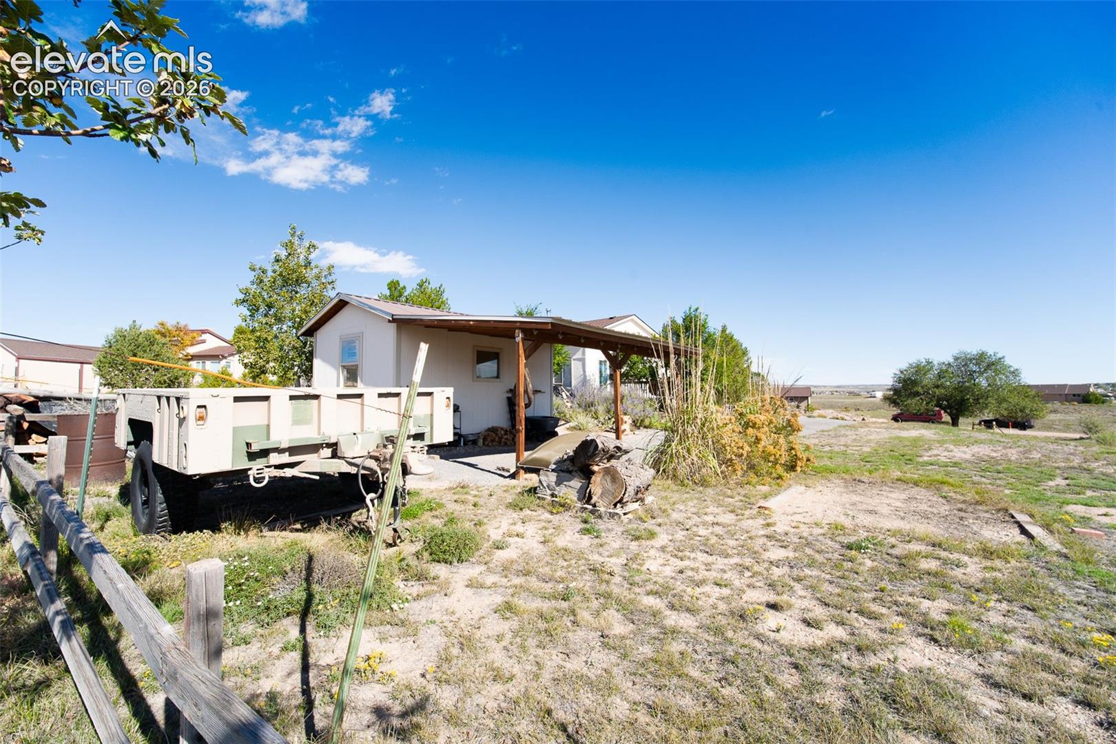 Exterior grounds featuring a wood-post covered patio, concrete slab, and perimeter split-rail fencing