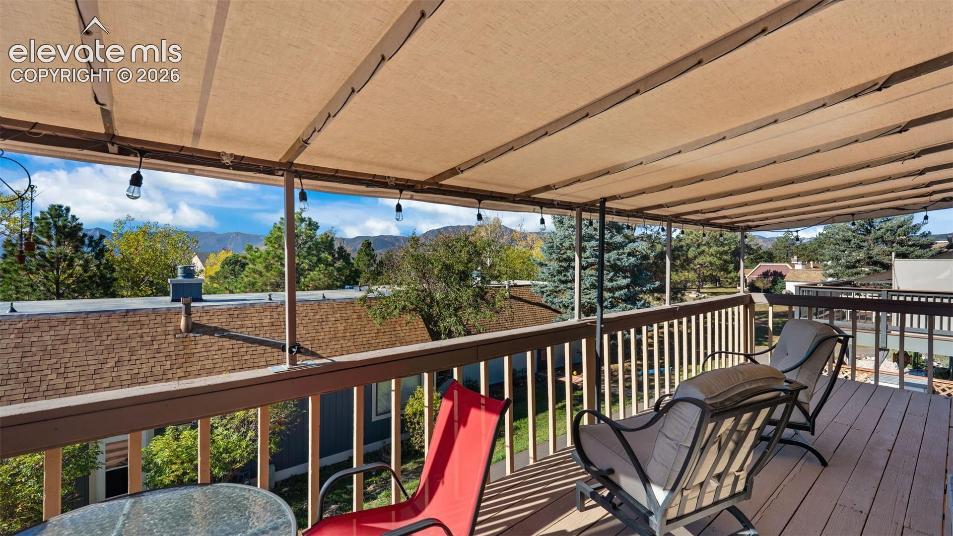 Elevated deck featuring a wood-style surface, protective canvas canopy, horizontal railing system, and mountain backdrop