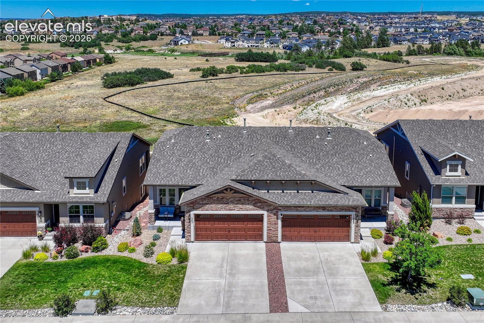 Aerial perspective highlights the home's attractive stone and stucco exterior, attached garage, and carefully maintained patio home setting.