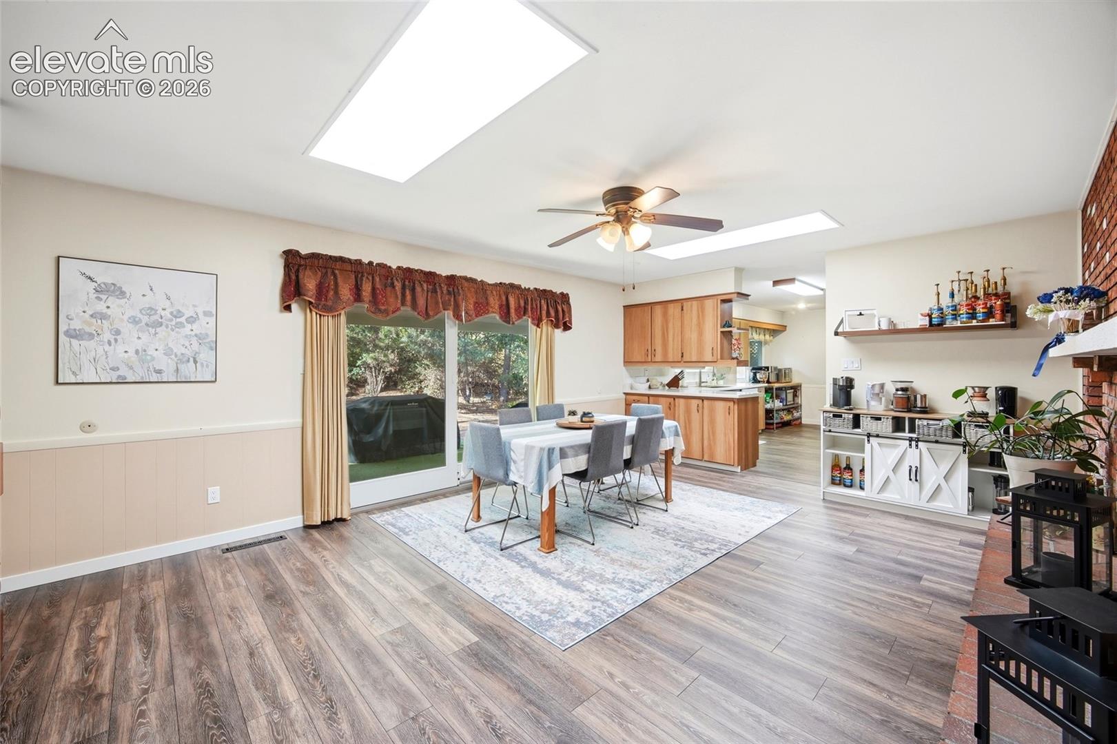 Wood-finish flooring, recessed lighting, sliding glass door, wooden cabinetry, and brick fireplace surround
