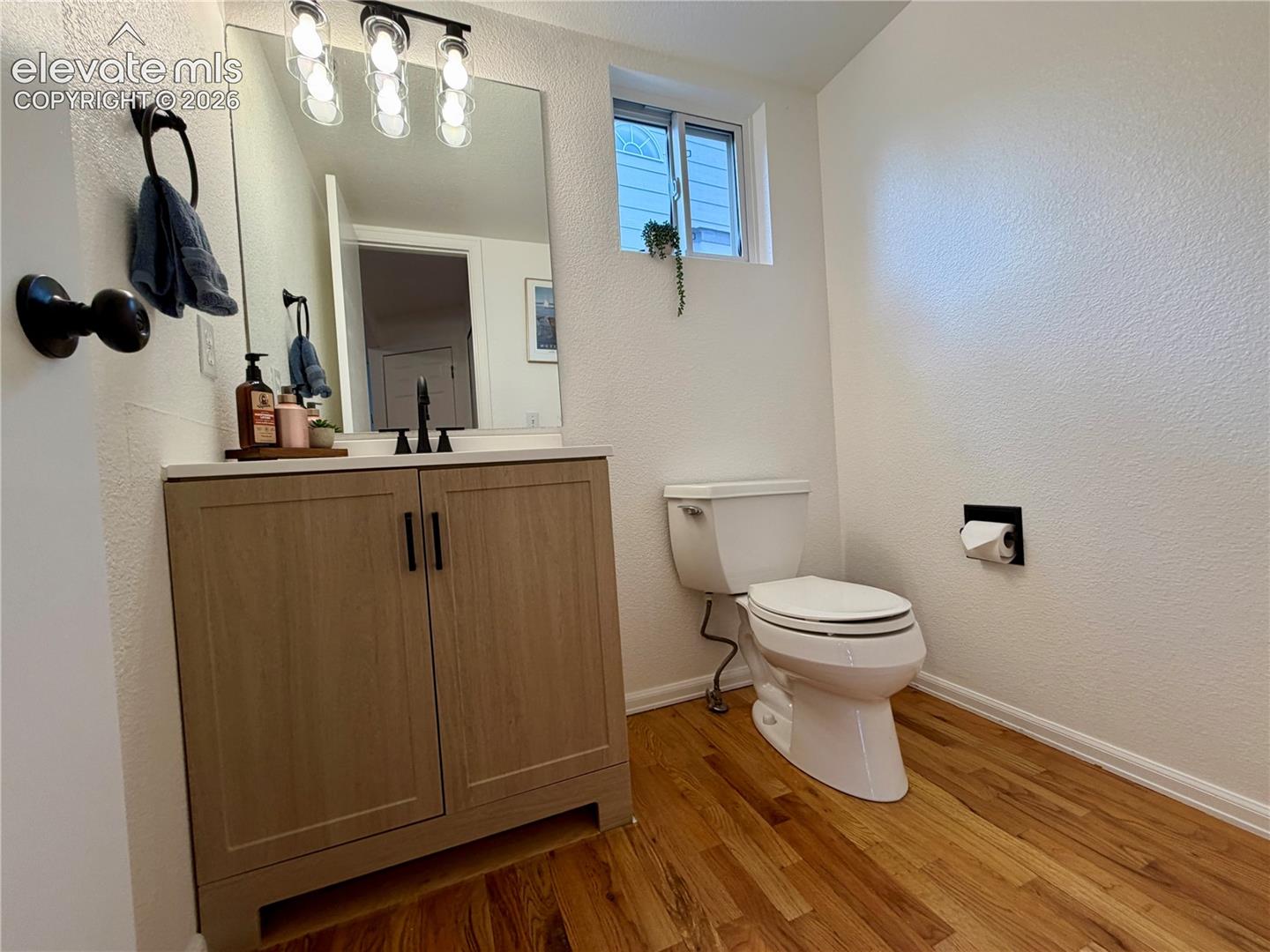 Bathroom with a wood-finish floor and a light wood-finish vanity
