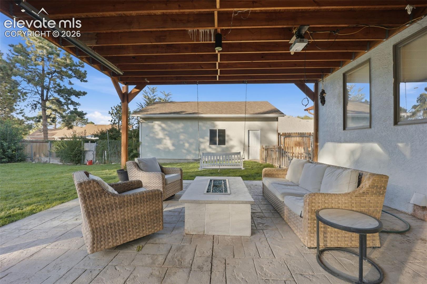Covered patio with stamped concrete flooring, exposed wood beam ceiling, and built-in fire pit