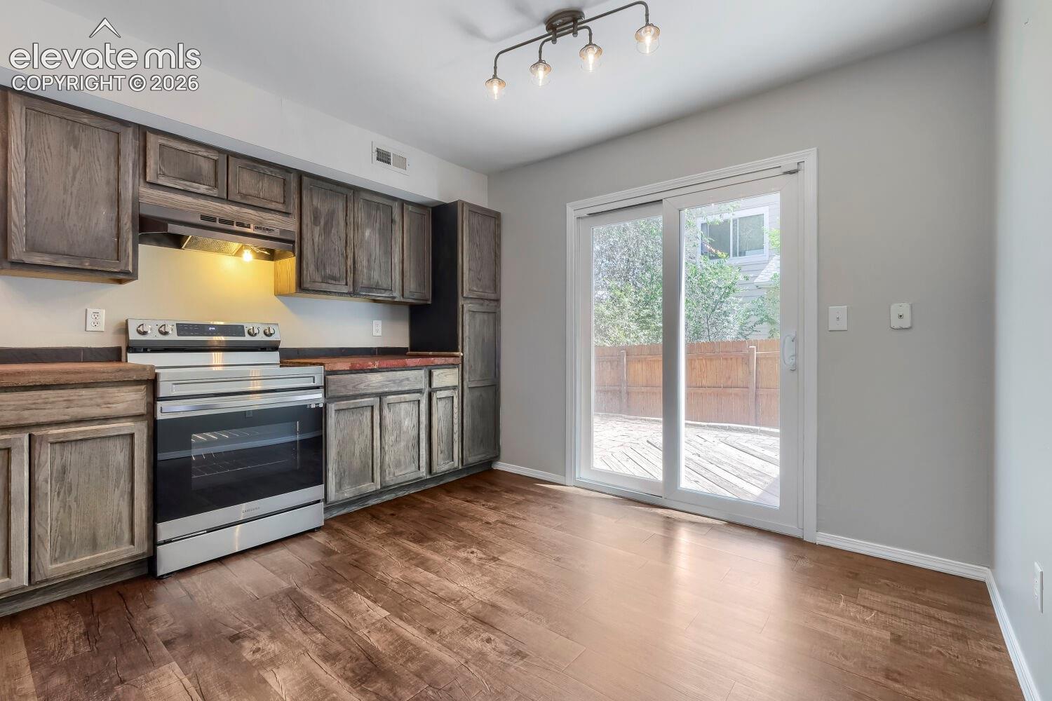 Kitchen featuring wood-finish flooring, gray shaker-style cabinetry, and dark countertops