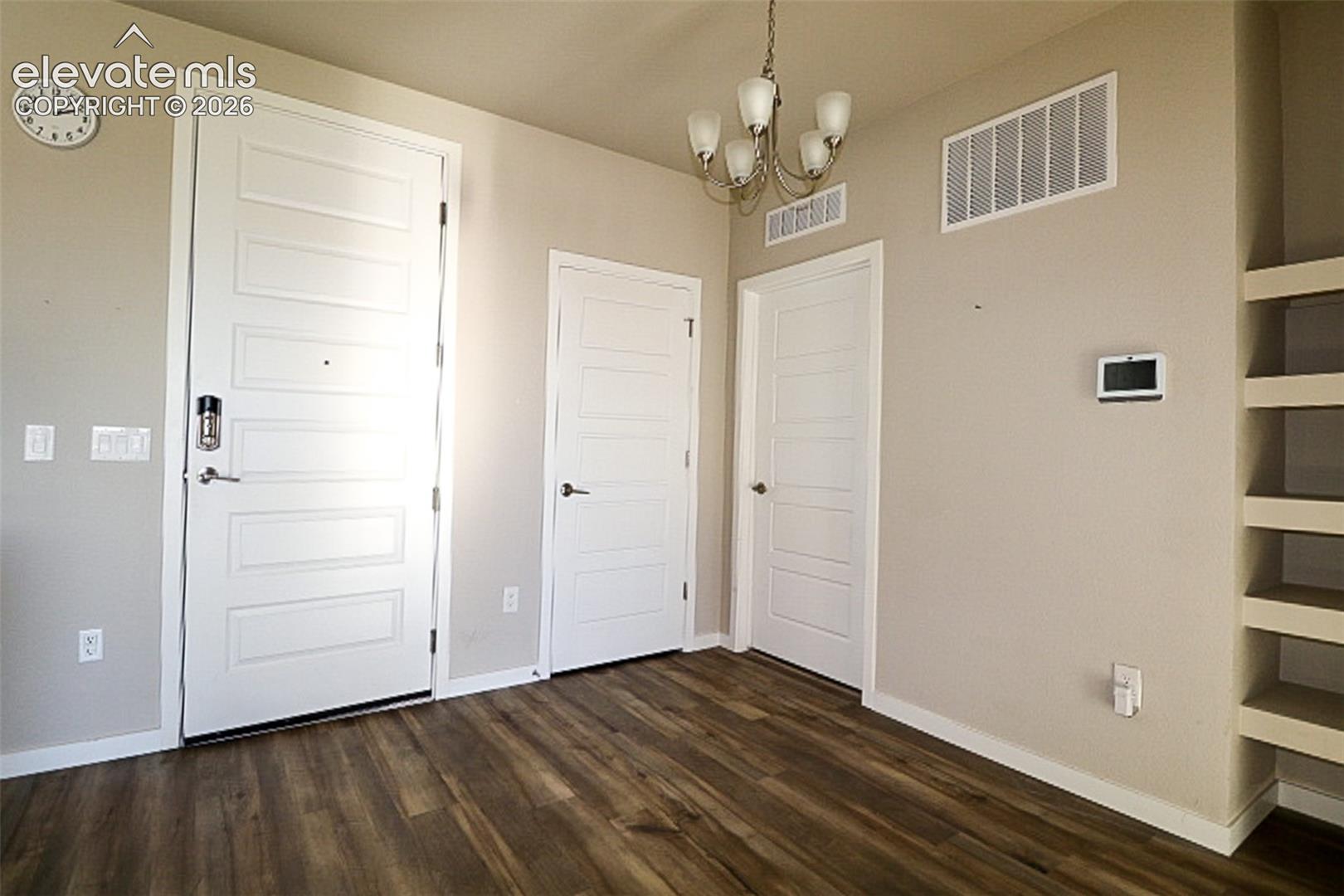Iflooring, a five-arm chandelier, two white four-panel interior doors, and built-in wall shelving
