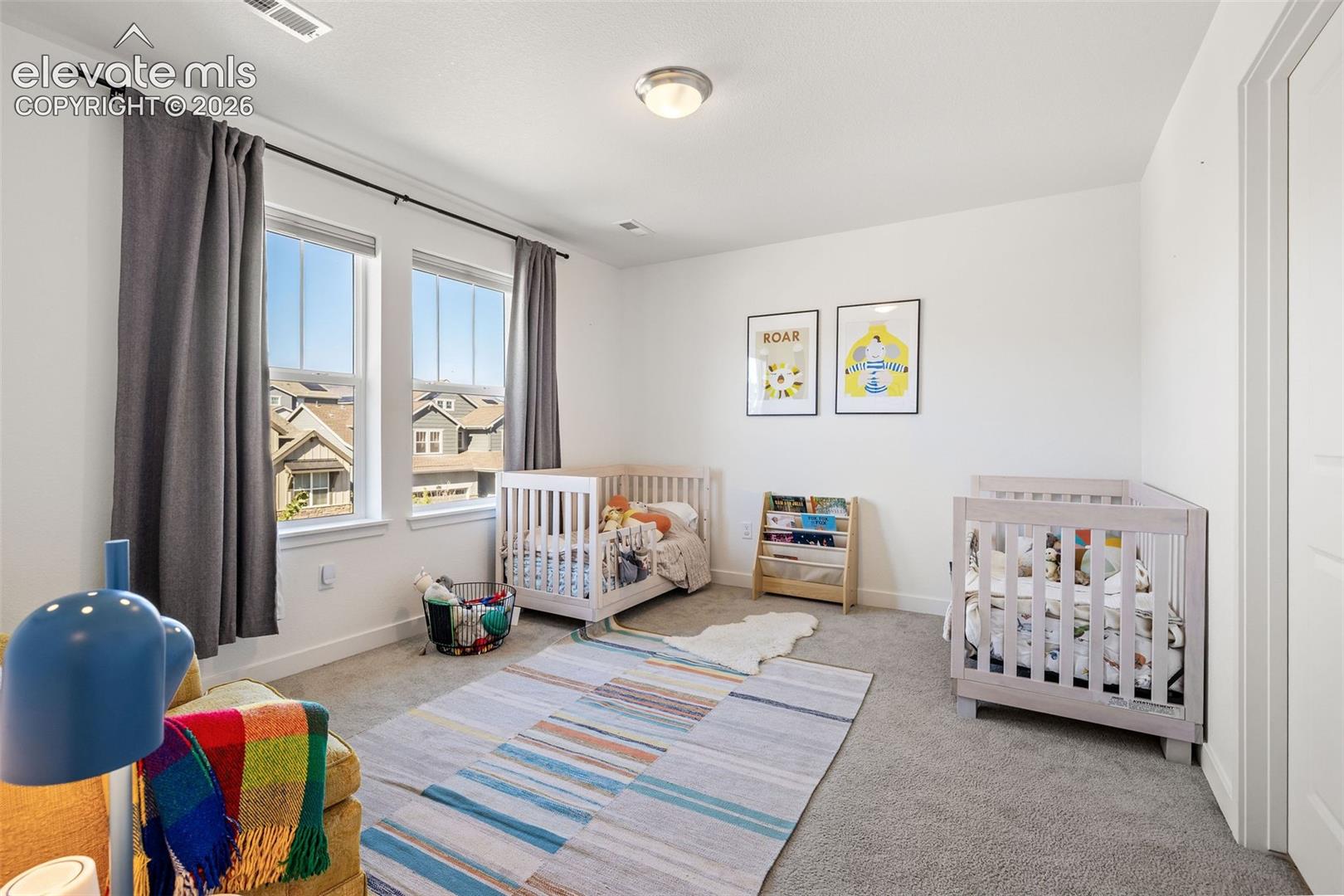 Bright room with neutral wall paint, two large windows, and gray carpeting