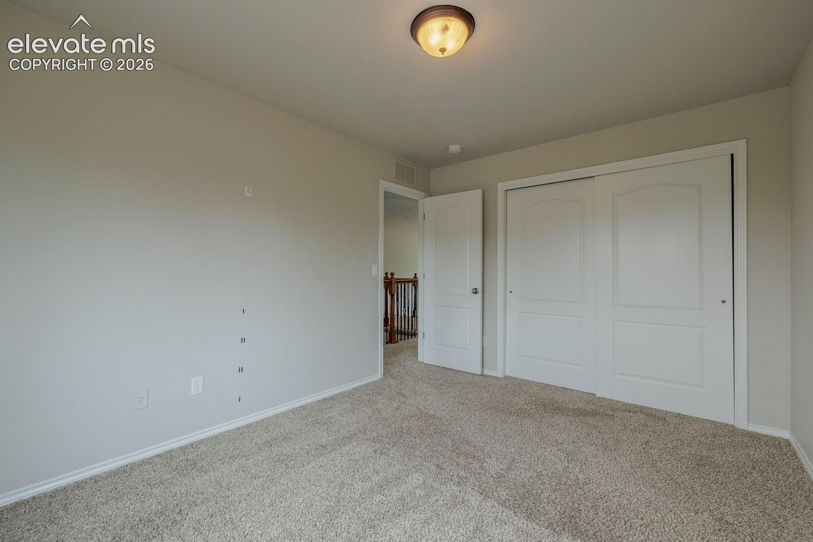 Spacious bedroom with neutral wall finishes, neutral carpet flooring, and dual sliding closet doors providing ample storage
