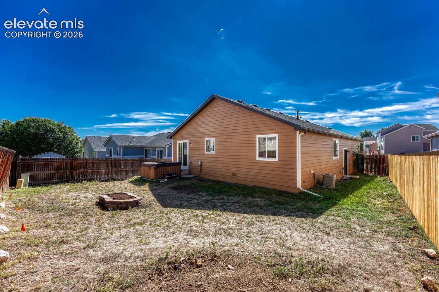 Rear view of home and fenced backyard.