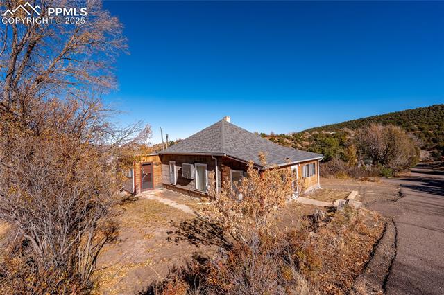 View of side of property featuring roof with shingles and a patio area