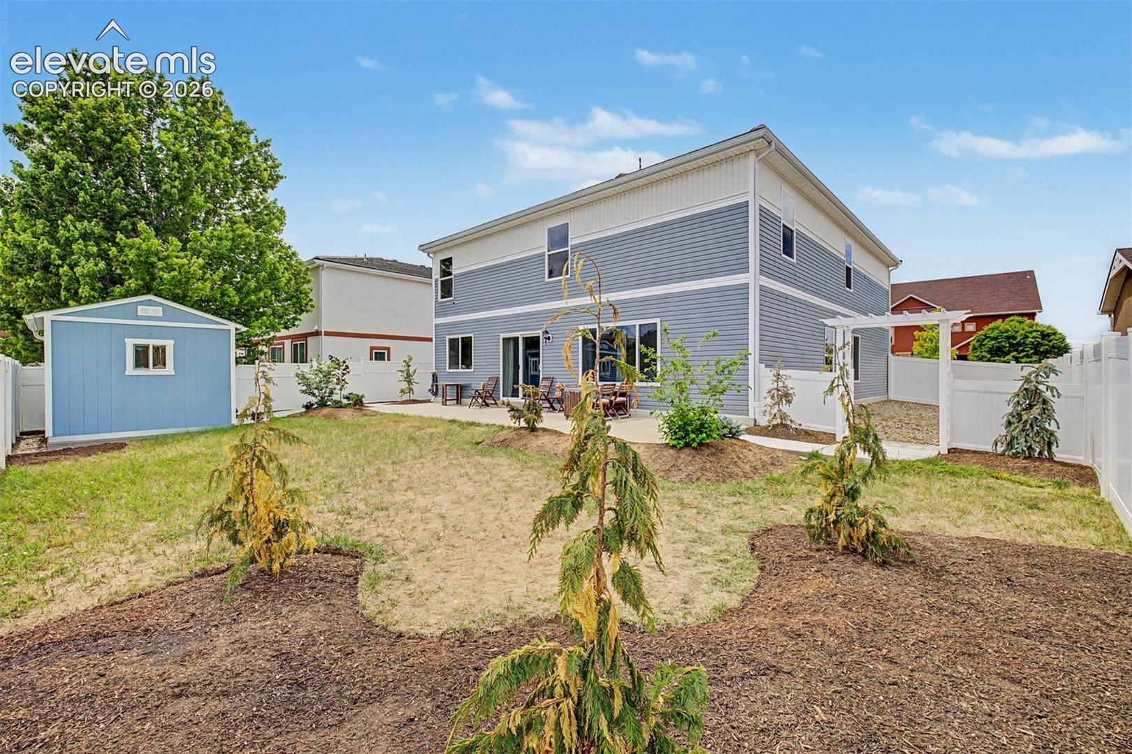 The full rear elevation showcases the home's impressive two-story scale and abundance of windows, which flood the interior with natural light and offer a beautiful backdrop to the backyard.