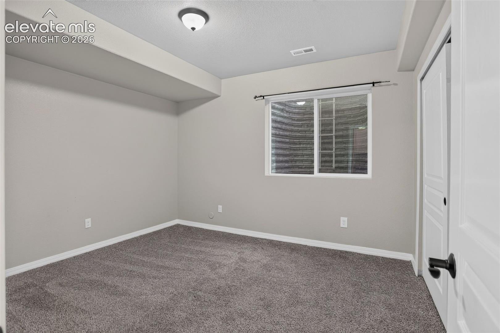 Window with white trim, gray carpet, and a white paneled door with black hardware