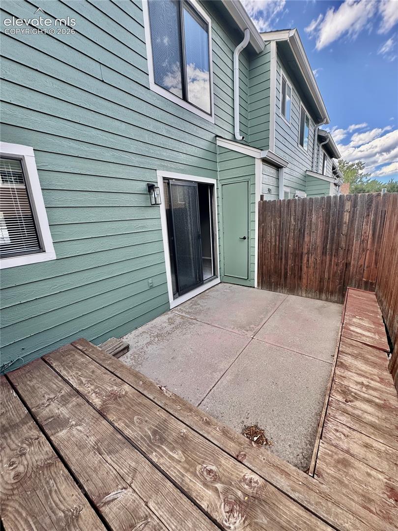 Private patio with concrete slab flooring, a sliding glass door, and a built-in wooden bench