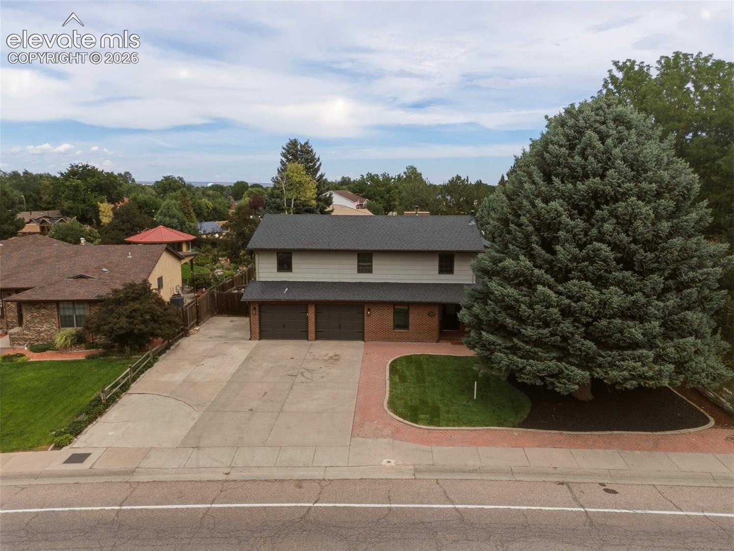 Two-story residence featuring a two-car garage, brick facade detailing, and a shingled roof