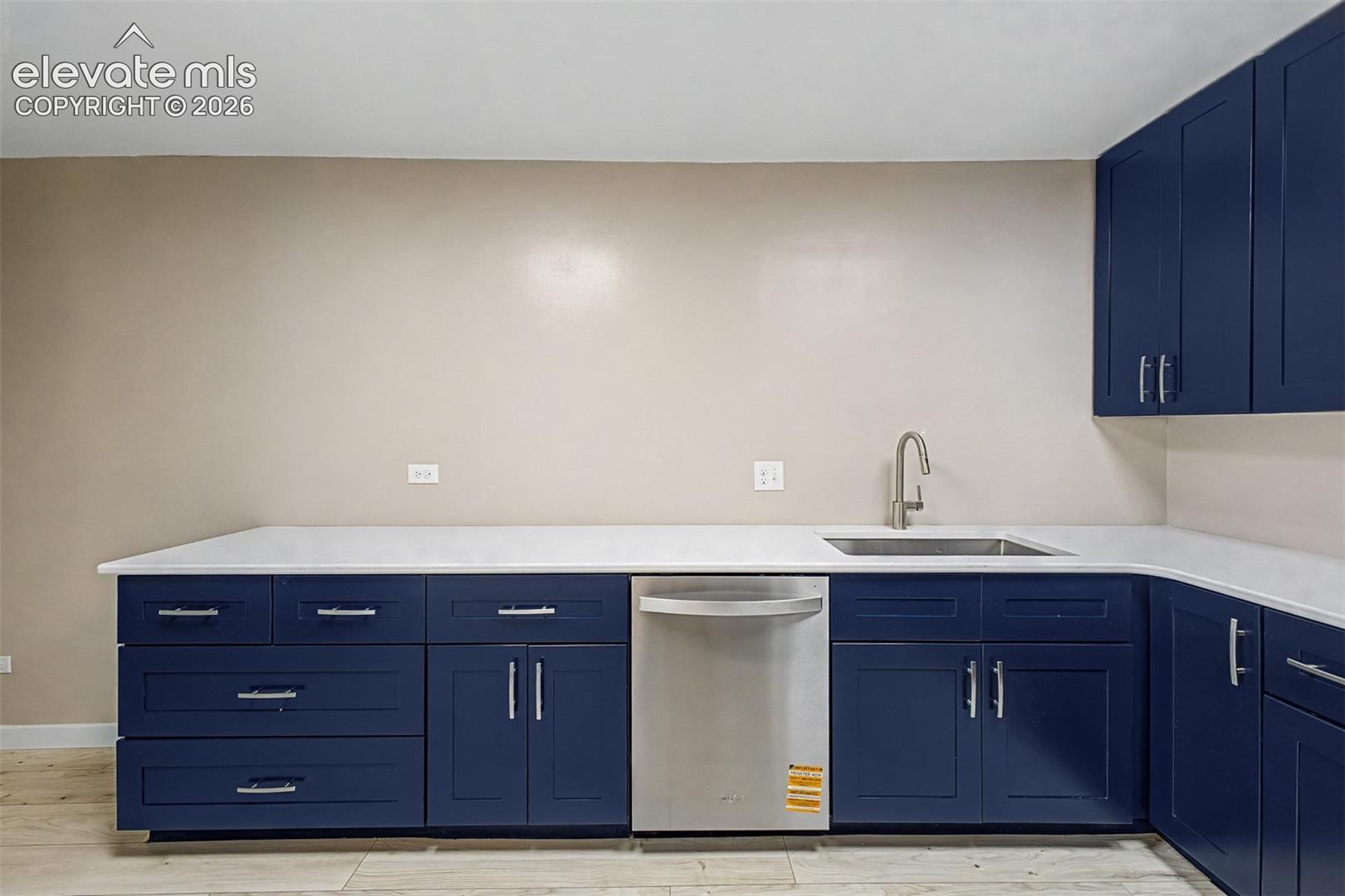 Kitchen featuring blue shaker-style cabinetry, white countertops, stainless steel sink with gooseneck faucet, and a stainless steel dishwasher