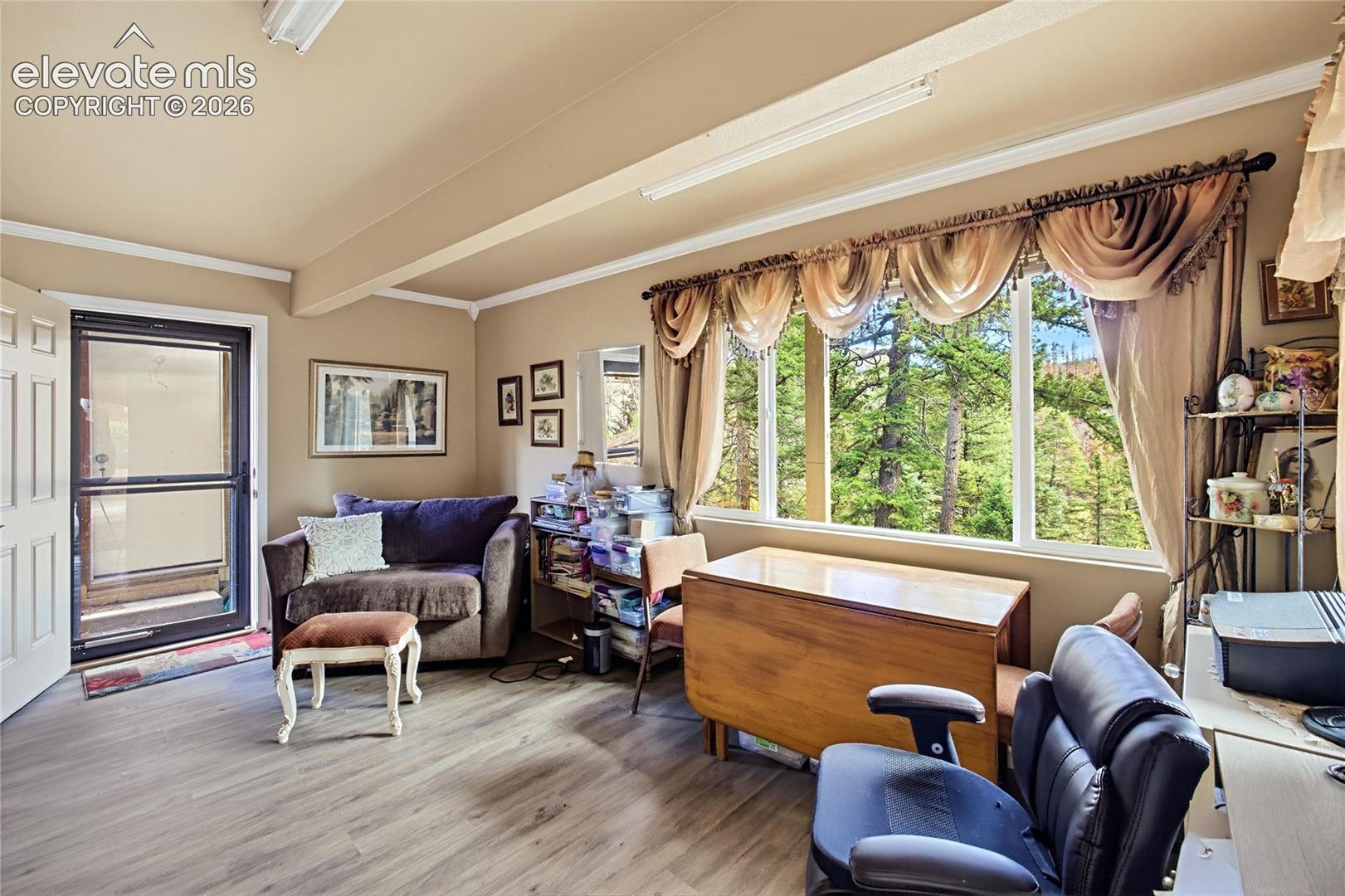 Interior space featuring wood-finish flooring, a vaulted ceiling, large picture window, and a glass-paneled exterior door