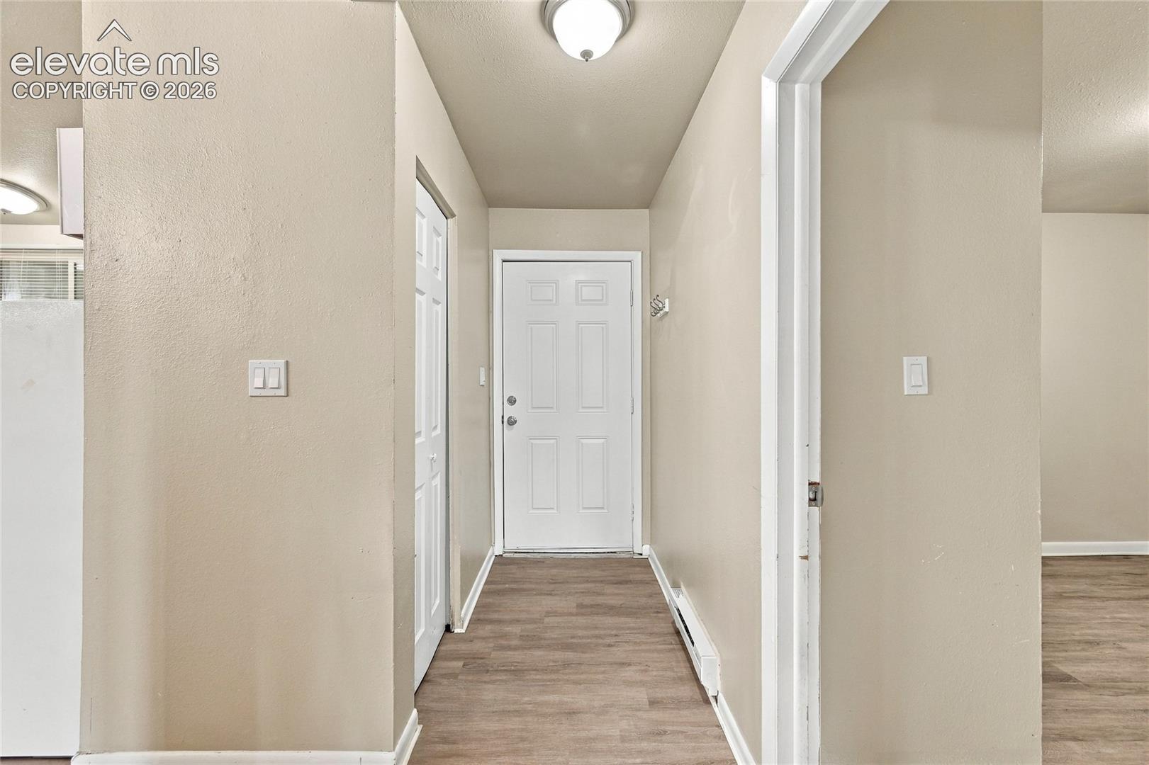 Entryway featuring a six-panel front door, wood-finish flooring, white door casings, and a flush-mount ceiling fixture